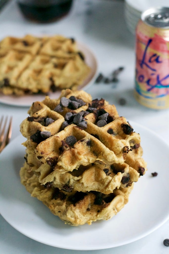 A stack of gluten-free waffles topped with chocolate chips and a can of sparkling water in the background.