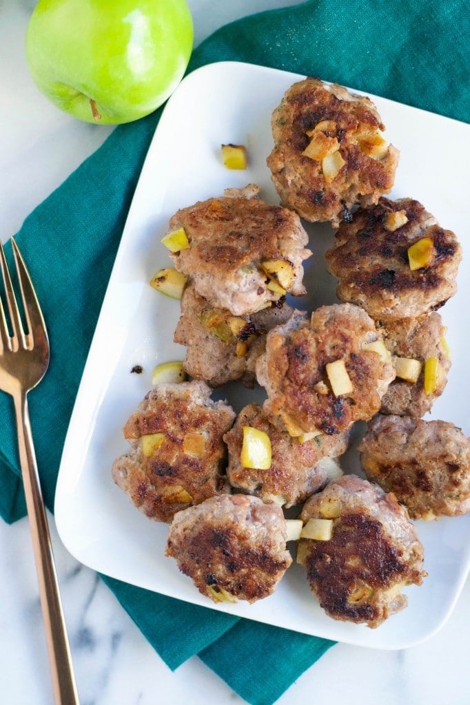 An overhead view of a platter filled with apple turkey breakfast sausage with a fork next to it. 