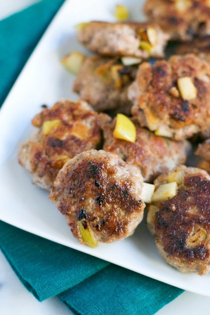 A pile of apple turkey breakfast sausage on a white platter. 