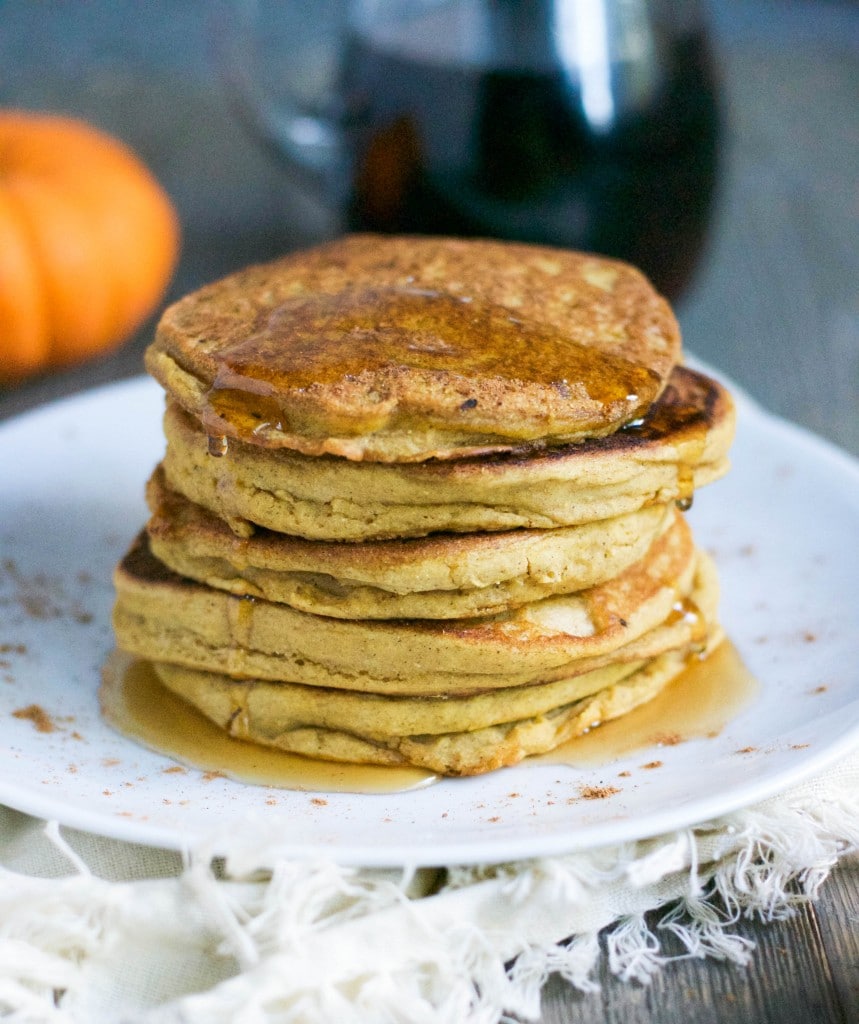 A stack of pumpkin pancakes with maple syrup dripping down the sides. 