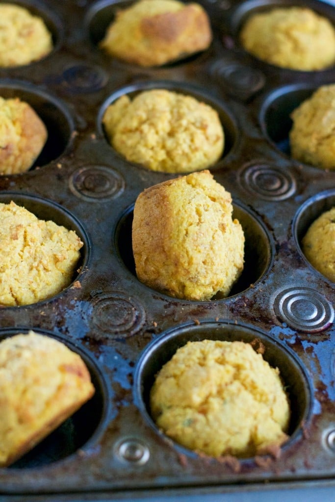 A muffin tin with sweet potato cornbread muffins in it.