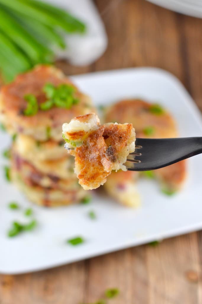 A fork with a bite of mashed potato cake on it.