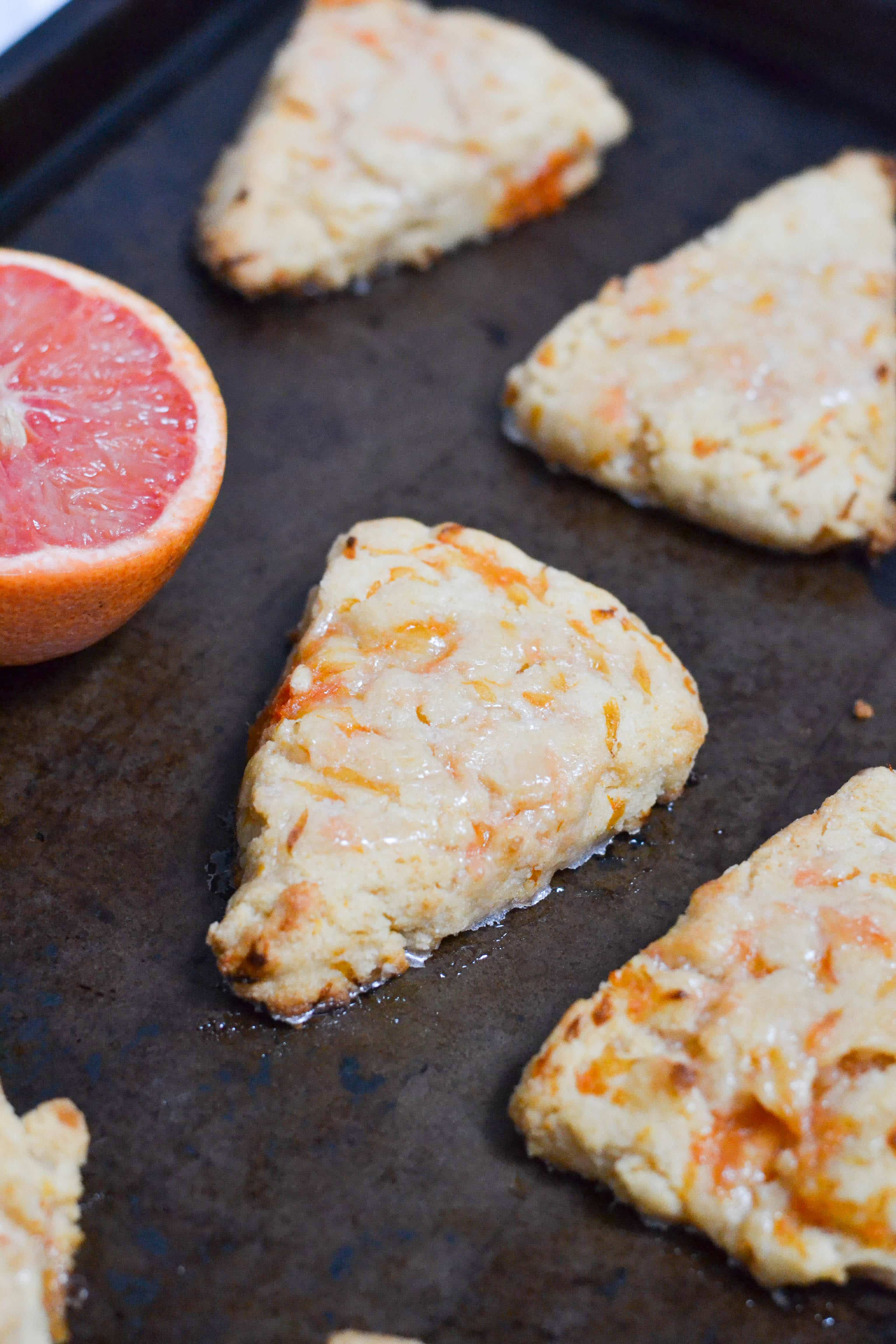 Grapefruit scones with glaze spaced out on a baking sheet. 