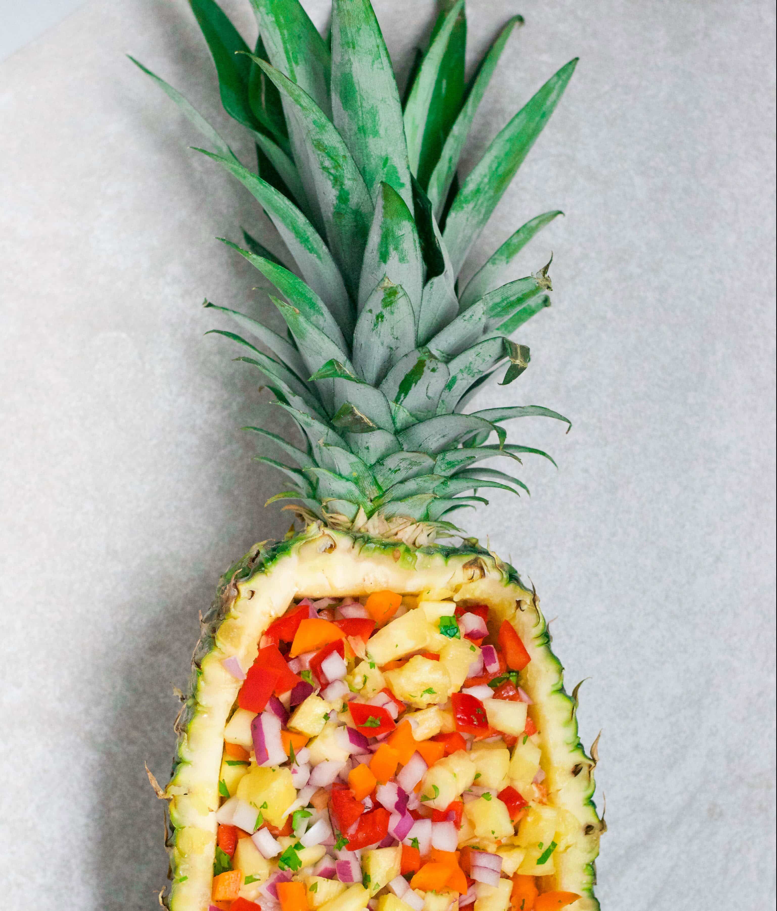 A pineapple cut in half filled with pineapple salsa. 