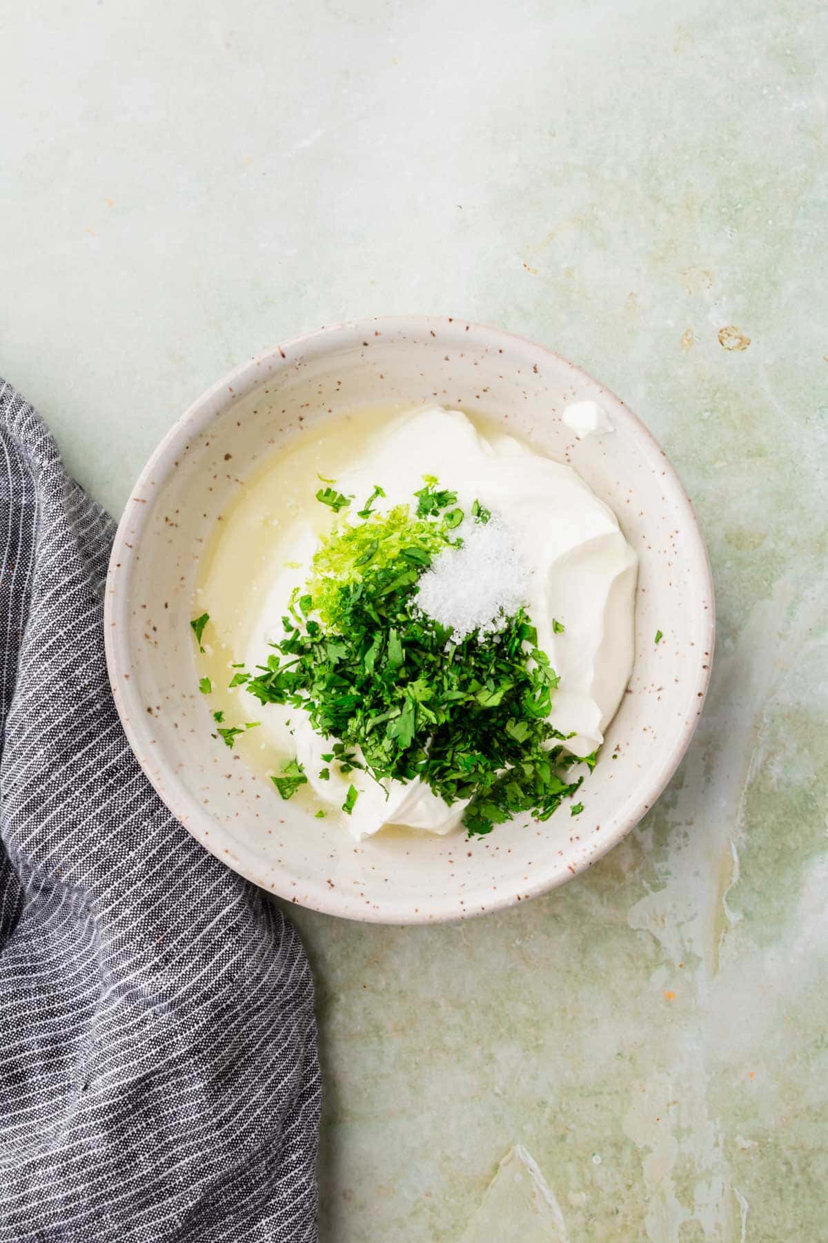 A bowl of sour cream, lime juice, cilantro and lime zest before mixing.