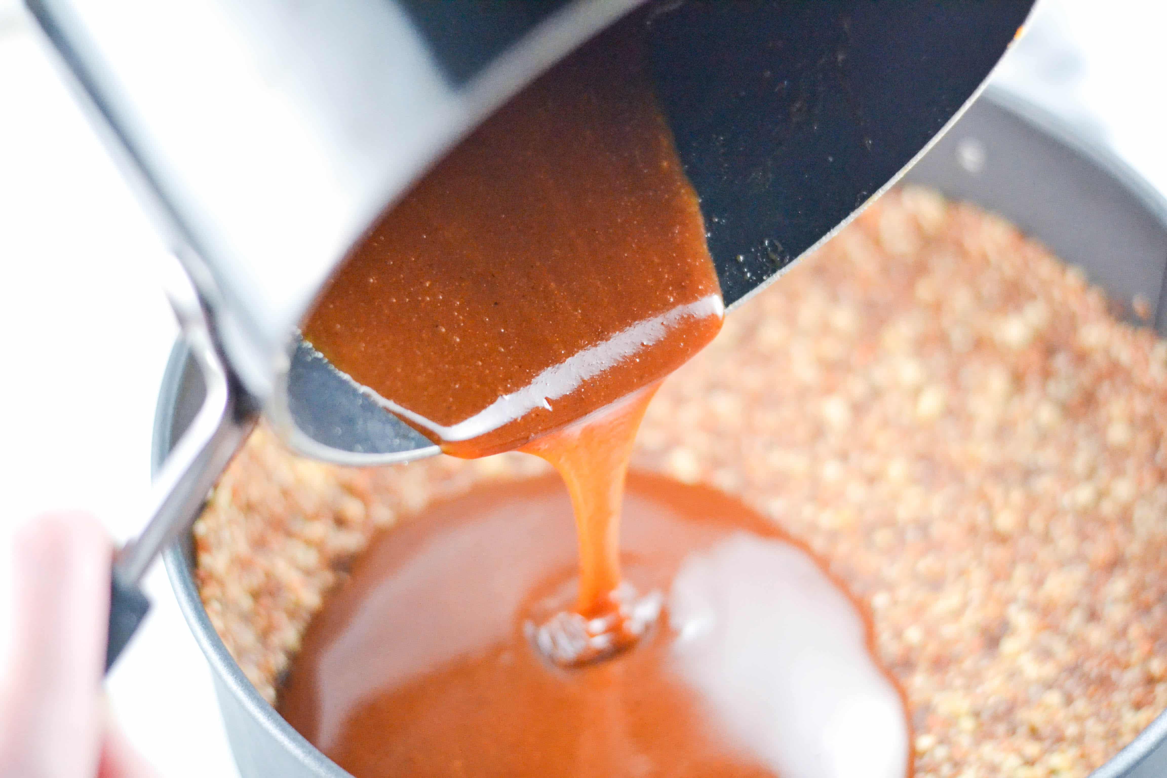 A saucepan of caramel sauce being poured over a nut crust. 