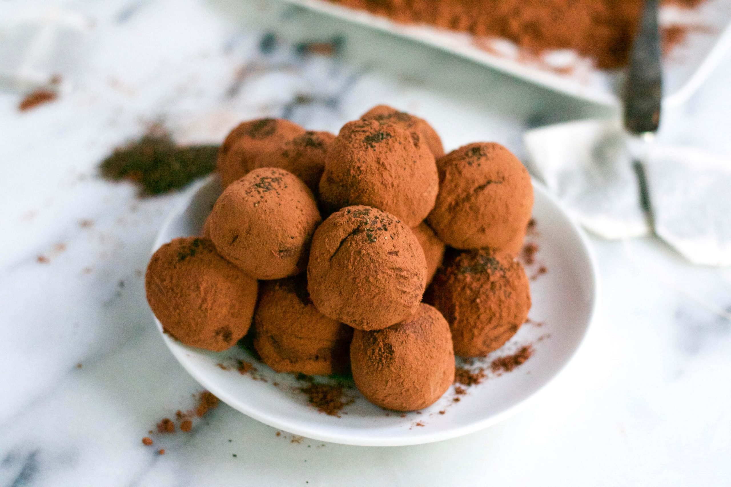 A plate of vegan earl grey chocolate truffles with cocoa powder sprinkled around. 