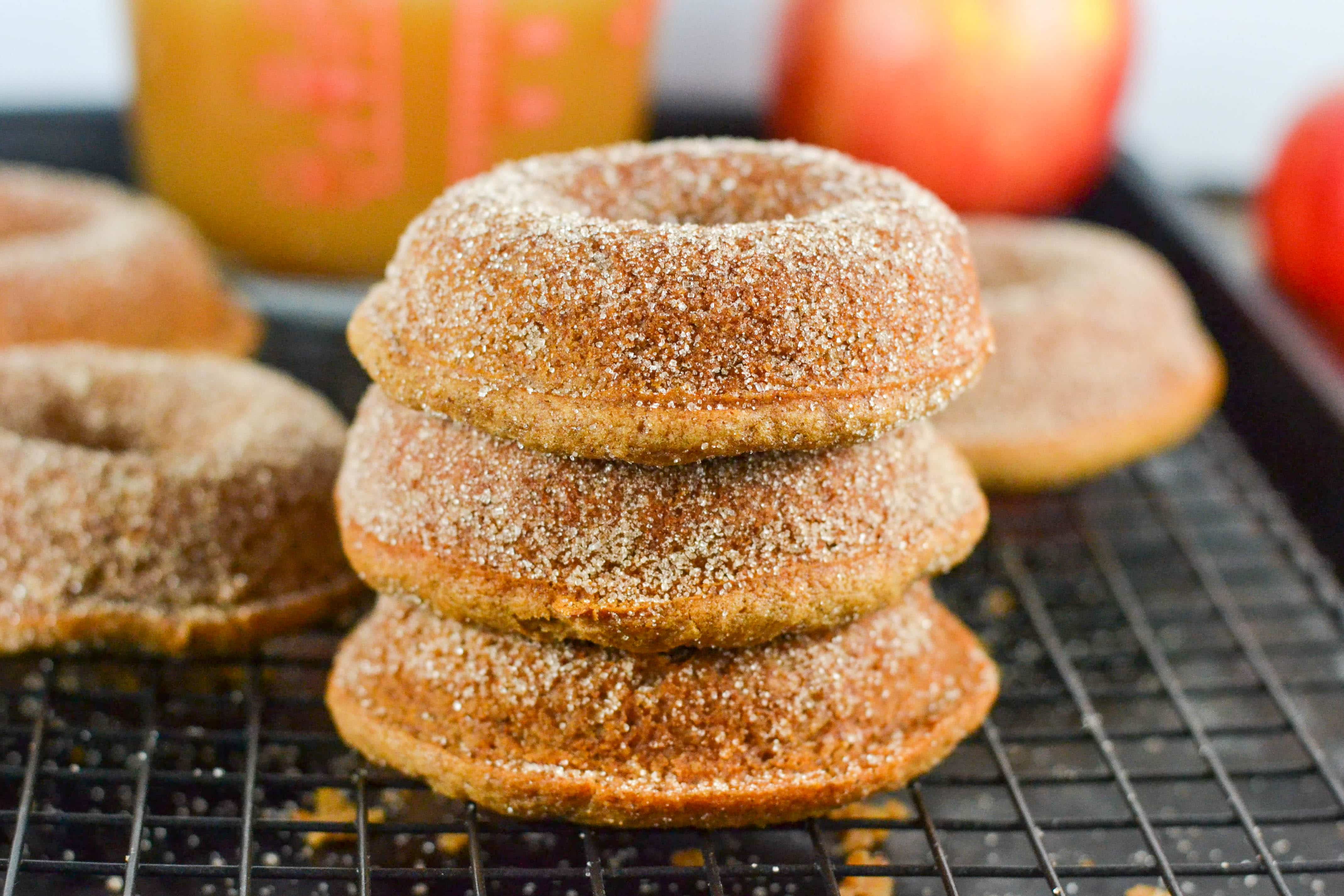A stack of three gluten-free apple cider donuts on a cooling rack. 