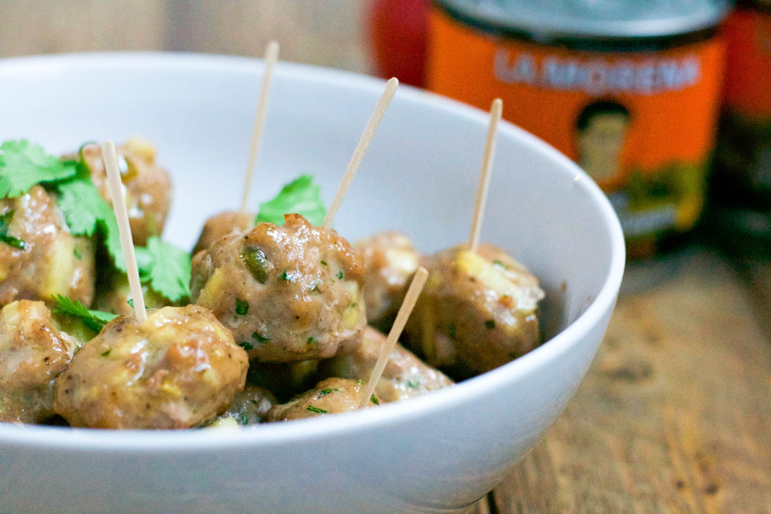 A bowl of apple jalapeño appetizer meatballs with toothpicks in them. 