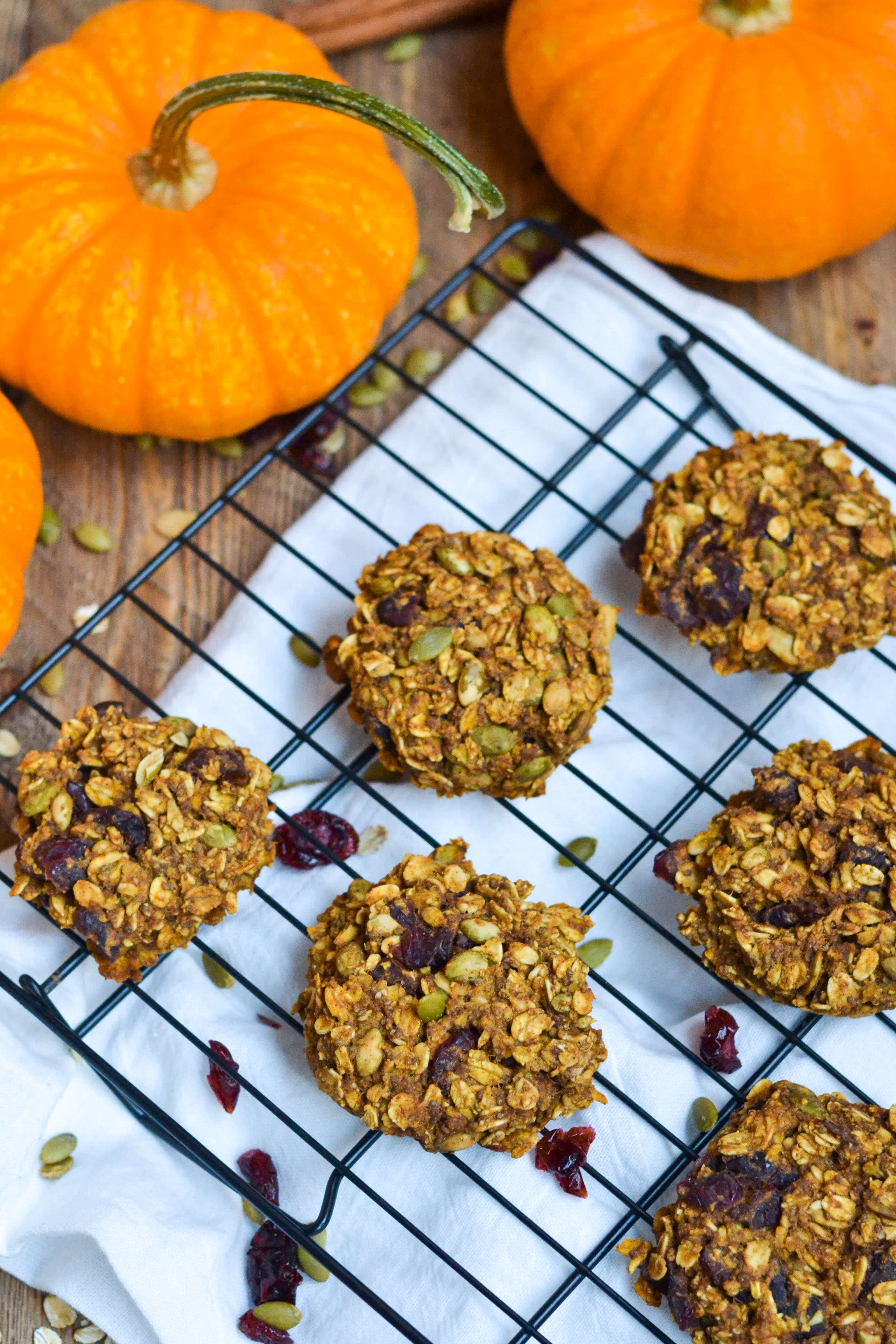 A cooling rack filled with Pumpkin Breakfast Cookies with cranberries and pepitas scattered around.
