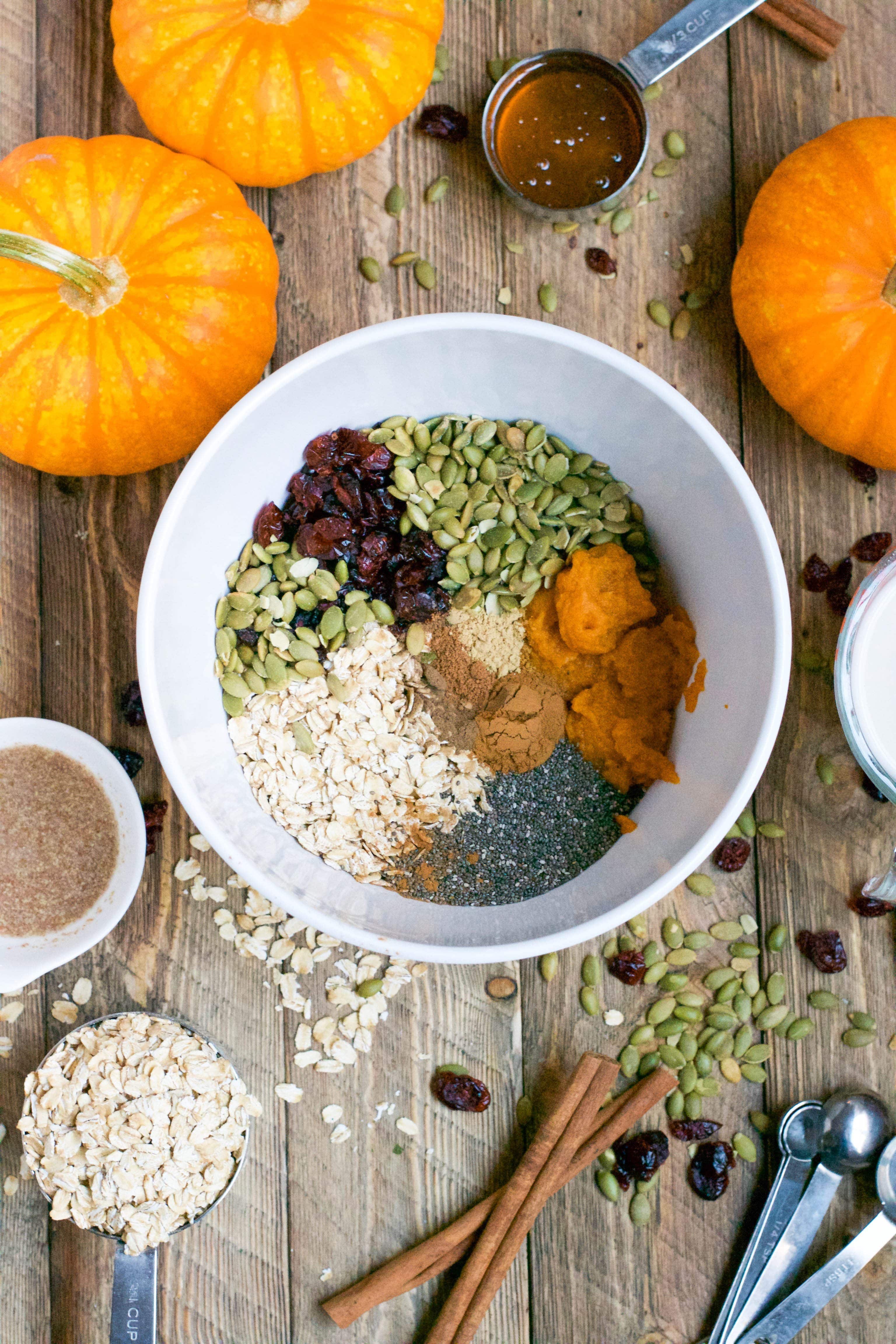 A bowl with oats, pepitas, cranberries, pumpkin, chia seeds, and spices to make pumpkin breakfast cookies. 