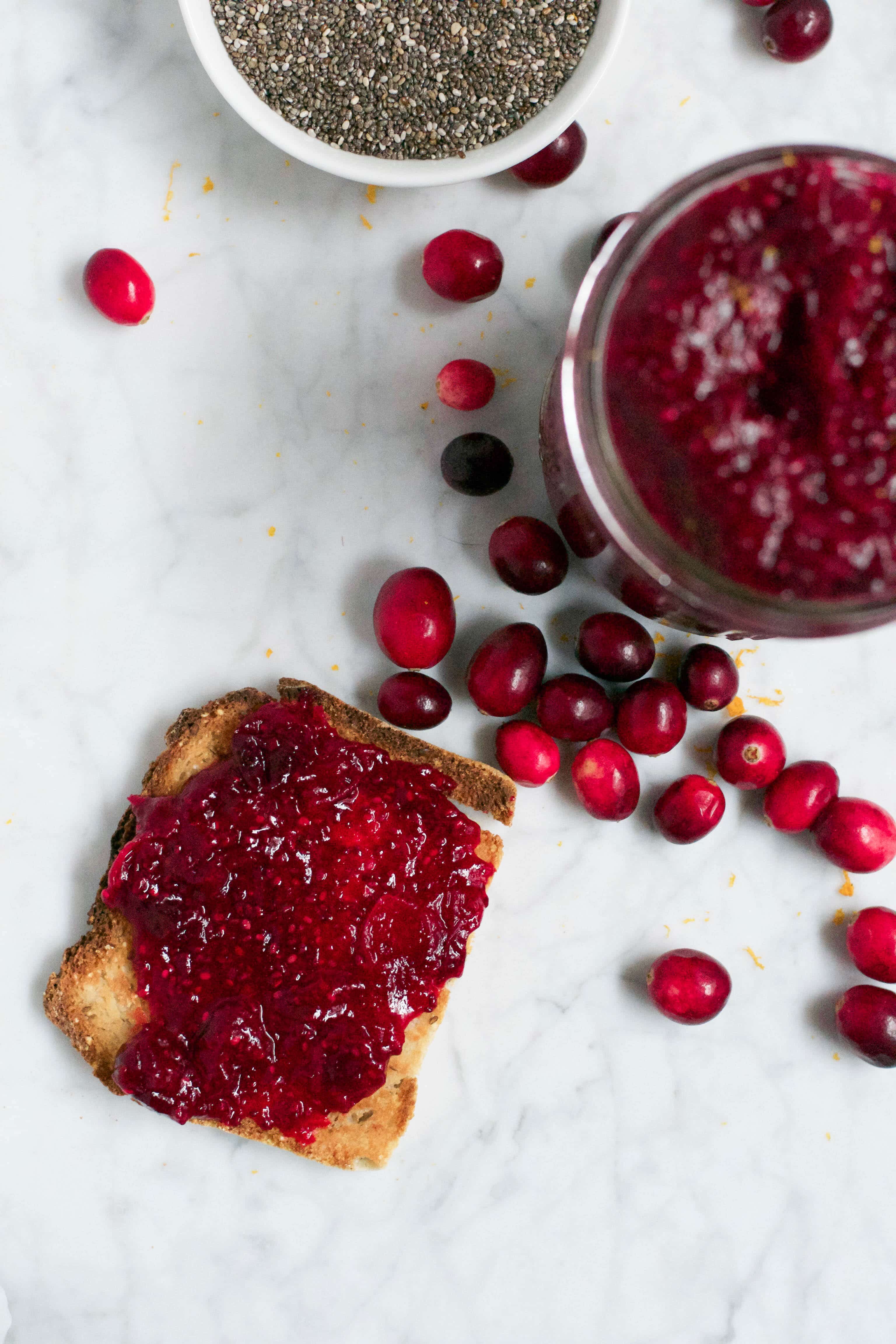 A piece of toast smeared with cranberry orange chia jam on it. 