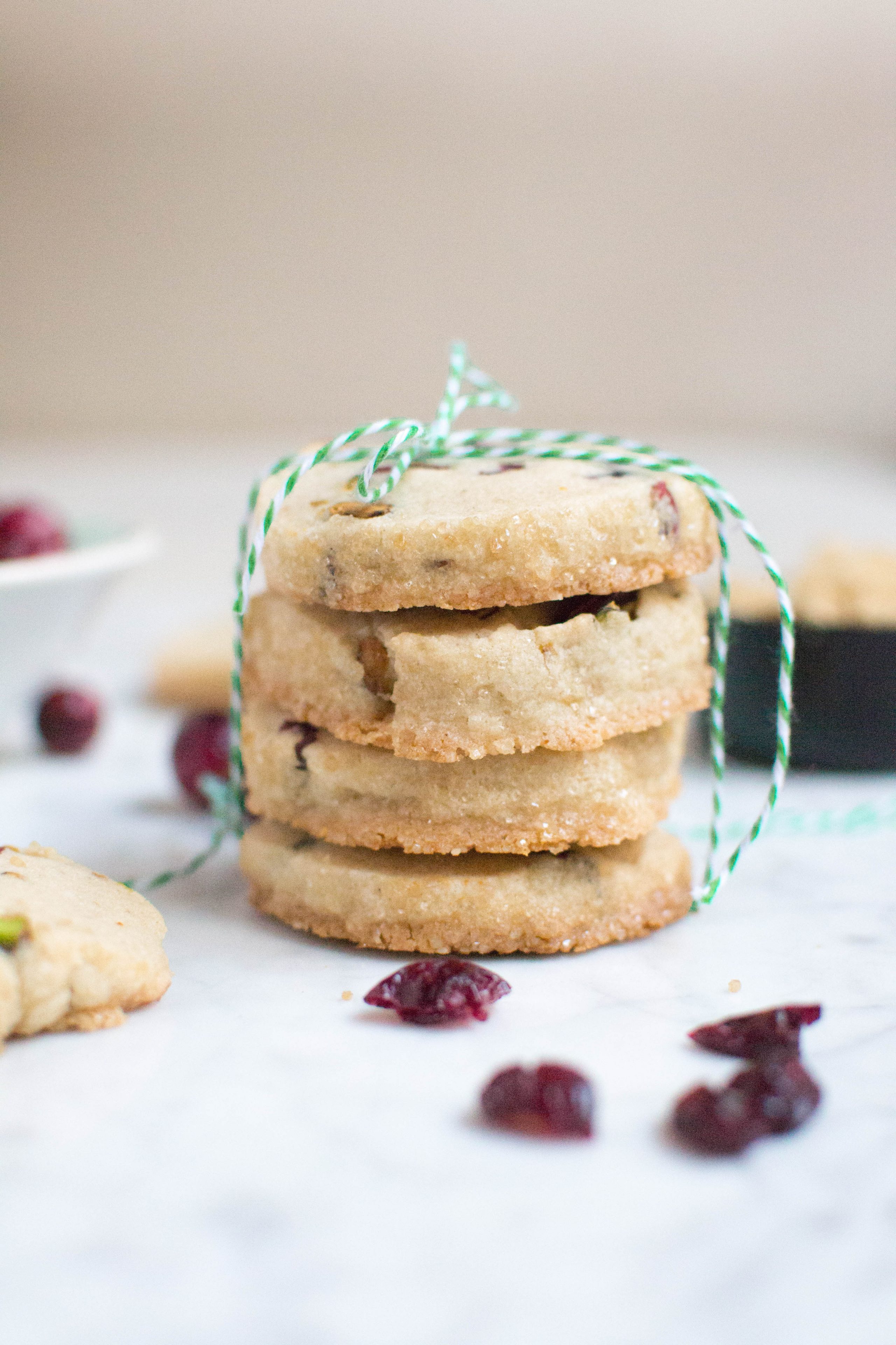 A stack of cranberry pistachio cookies tied with green and white twine. 