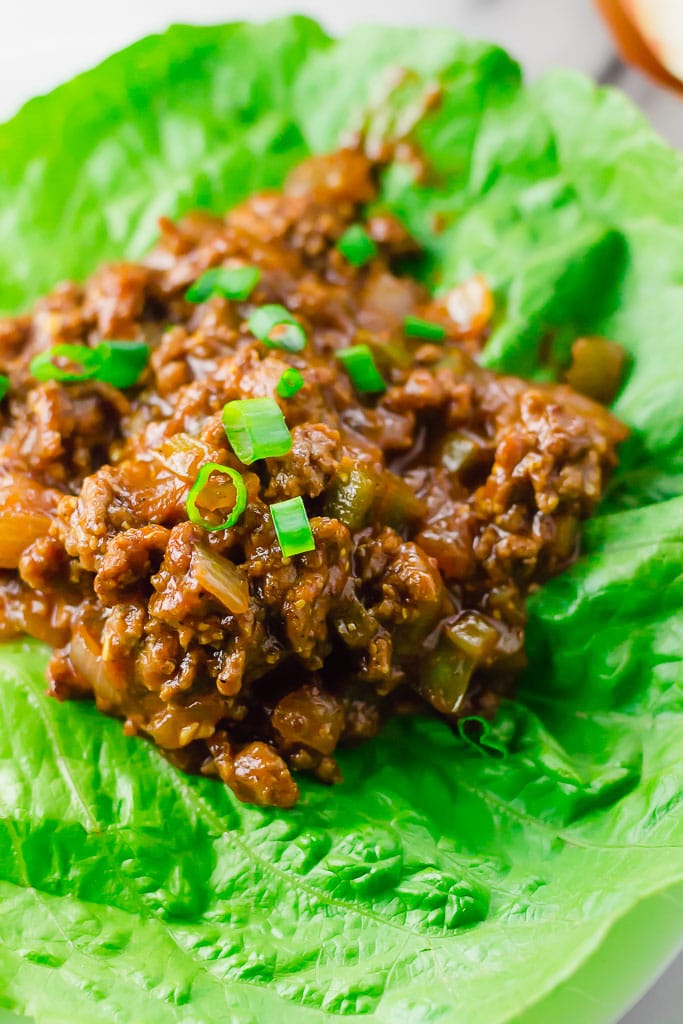 Sloppy Joe Lettuce Wraps (GF, DF) - a close up shoot of sloppy joe ground beef flavored with tomato sauce, tamari sauce, mustard, apple cider vinegar, brown sugar cooked and sitting on top of a large green lettuce leaf and sprinkled with chopped green onion
