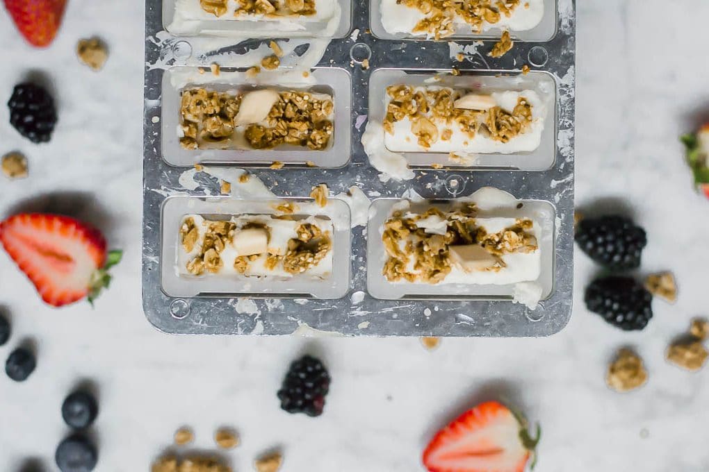 Aerial view of gluten-free and dairy-free yogurt and granola breakfast popsicles in the popsicle mold ready for freezing. 