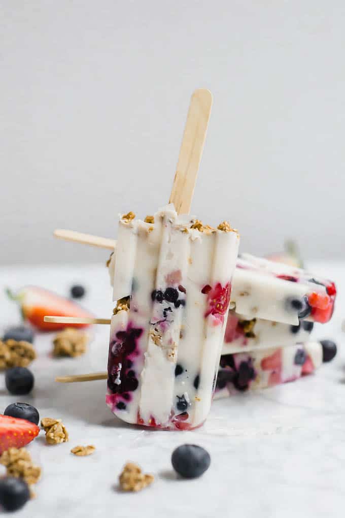 Front view of a breakfast parfait popsicle with fresh berries and granola.