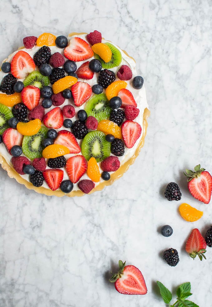 An aerial view of a gluten-free fruit tart topped with mandarin oranges, strawberries, blueberries, blackberries, raspberries, and kiwi. 