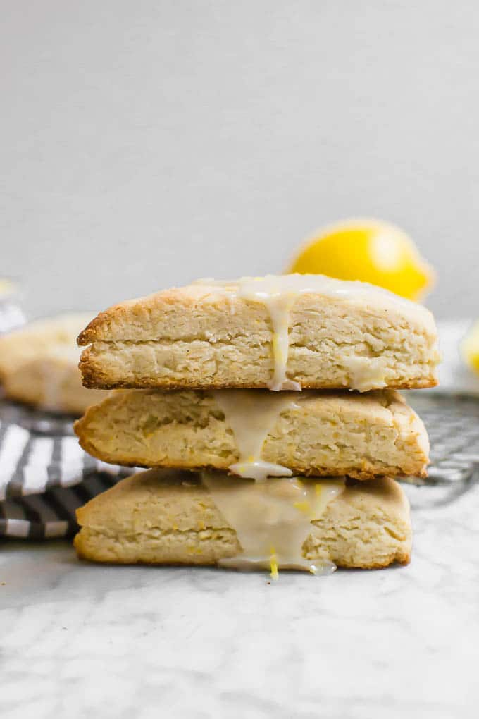 A straight on view of a stack of three gluten-free vegan lemon scones with lemon glaze dripping down the side. 