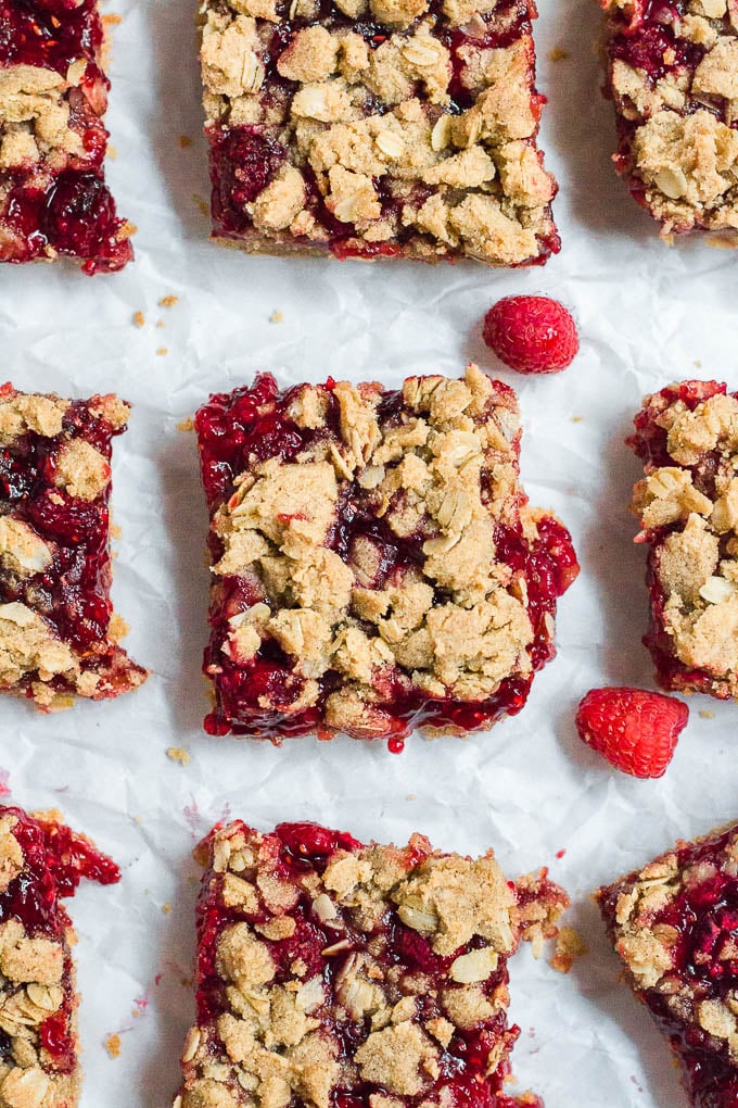 Aerial view of nine gluten-free, dairy-free, vegan raspberry crumb bars on a table. 