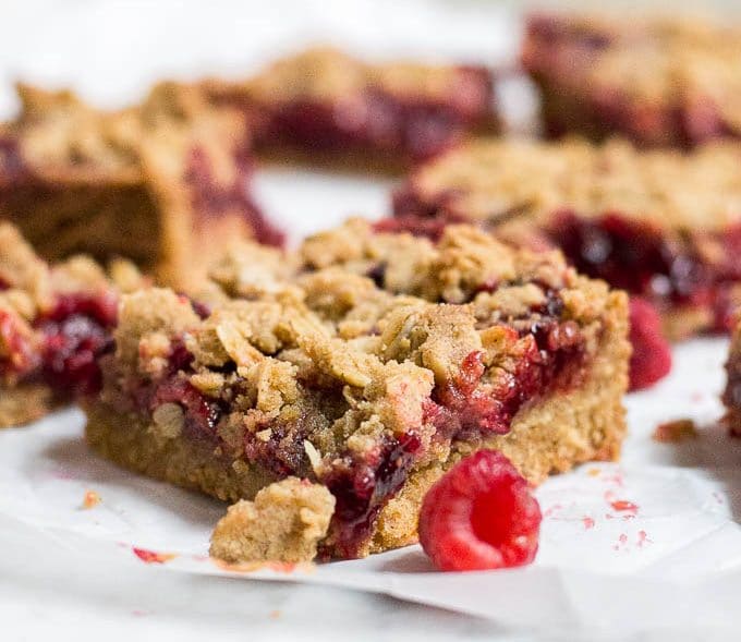 Straight on view of a raspberry crumb bar with raspberry filling and oat topping.