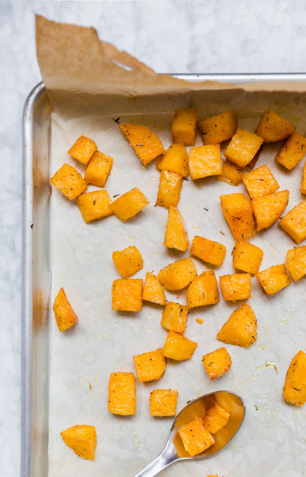 A baking sheet with gluten-free polenta croutons on a white table.