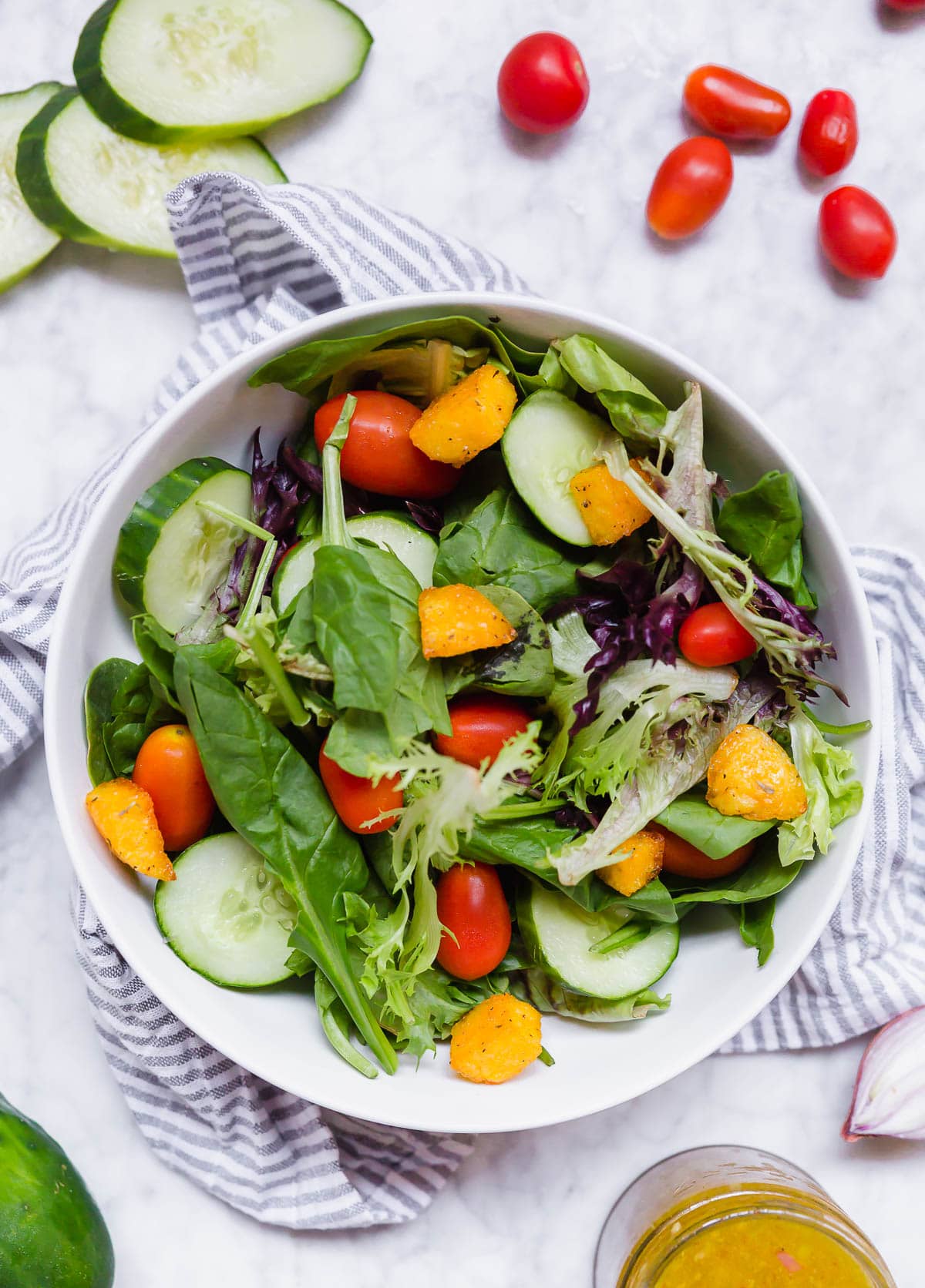 A bowl of salad with easy polenta croutons, tomatoes and cucumbers.