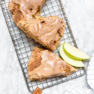 Gluten-Free vegan apple cinnamon scones on a cooling rack with granny smith apple slices and cinnamon sticks.
