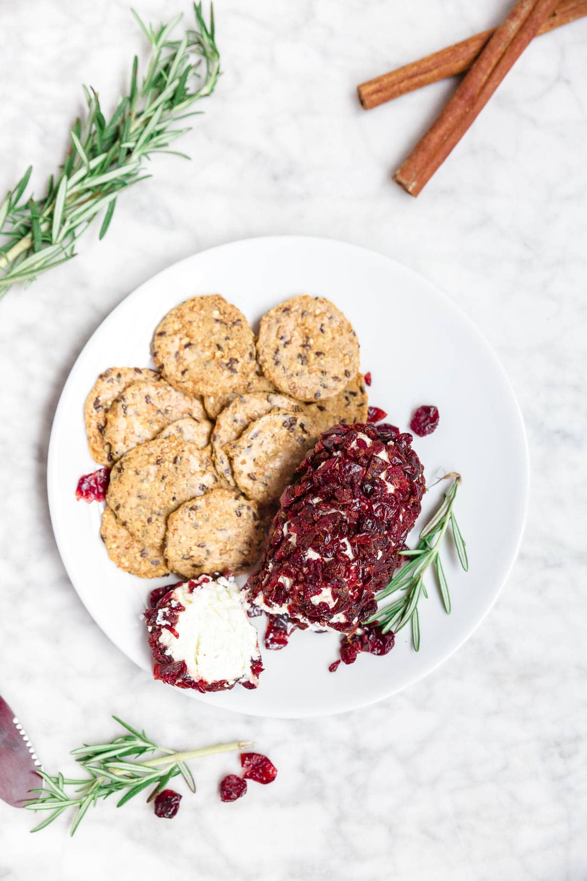 A plate of gluten-free crackers and cranberry goat cheese log. 