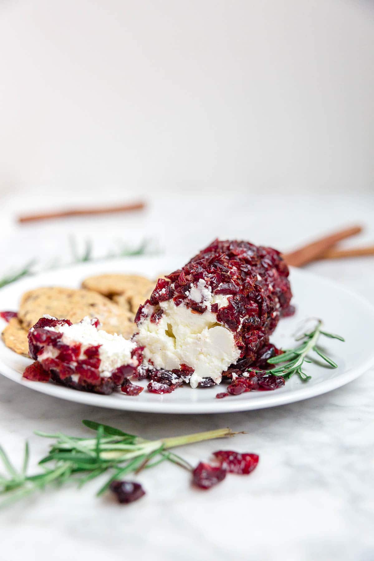 Cranberry cinnamon goat cheese log on a plate with gluten-free crackers.