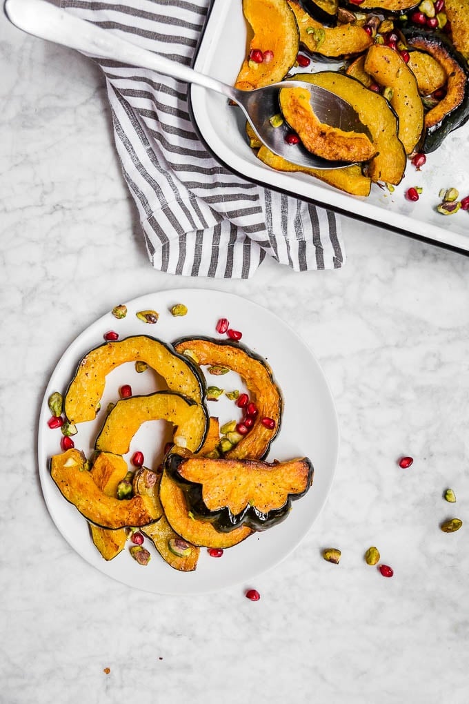 A plate of roasted acorn squash pomegranate and toasted salted pistachios.