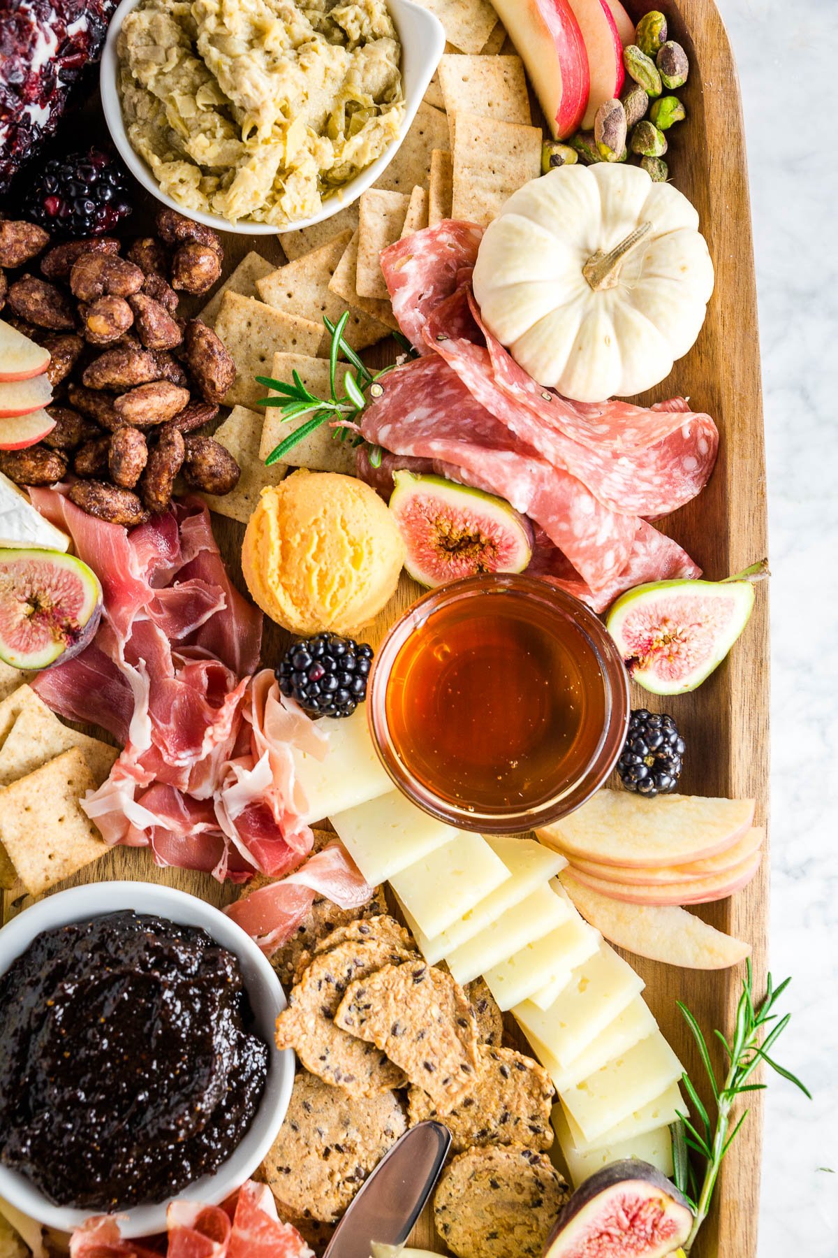 A wooden cheese board with gluten-free meats, cheeses and crackers. 