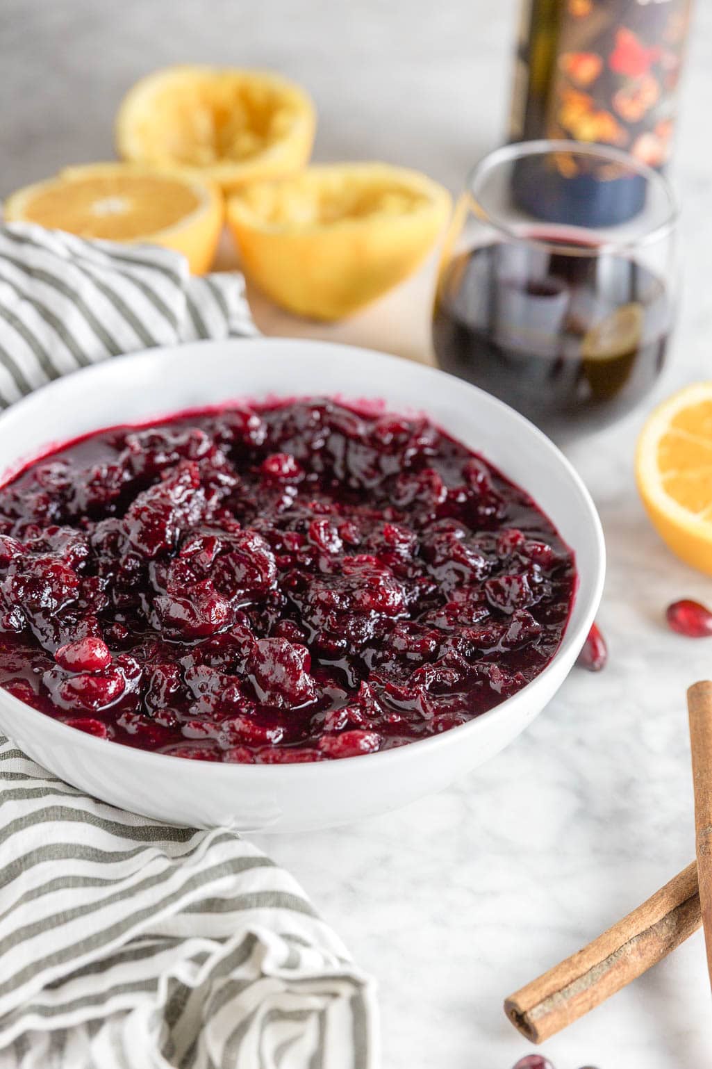 A white bowl filled with red wine cranberry sauce with orange juice, cinnamon and sugar for an easy holiday recipe.