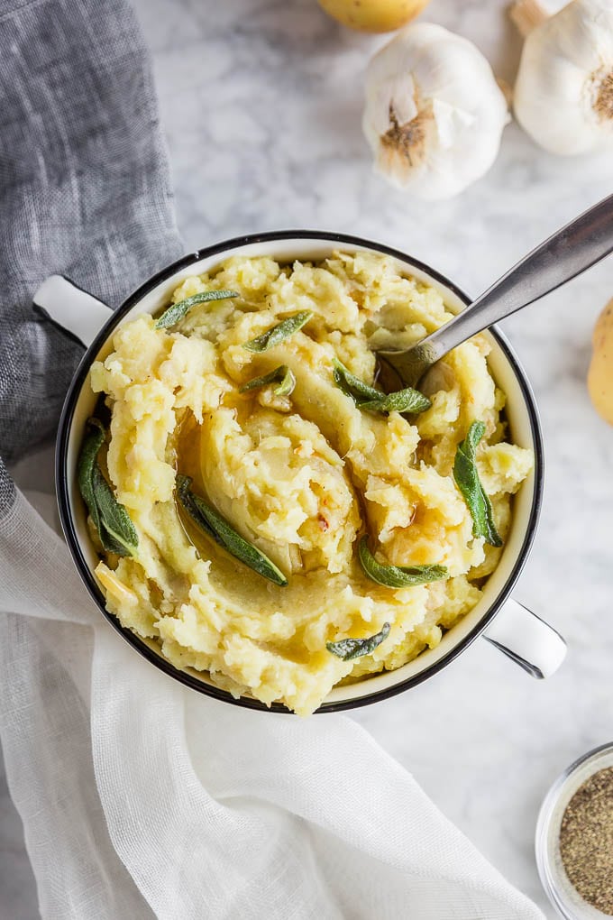 A bowl of roasted garlic mashed potatoes with brown butter and fresh sage leaves. 