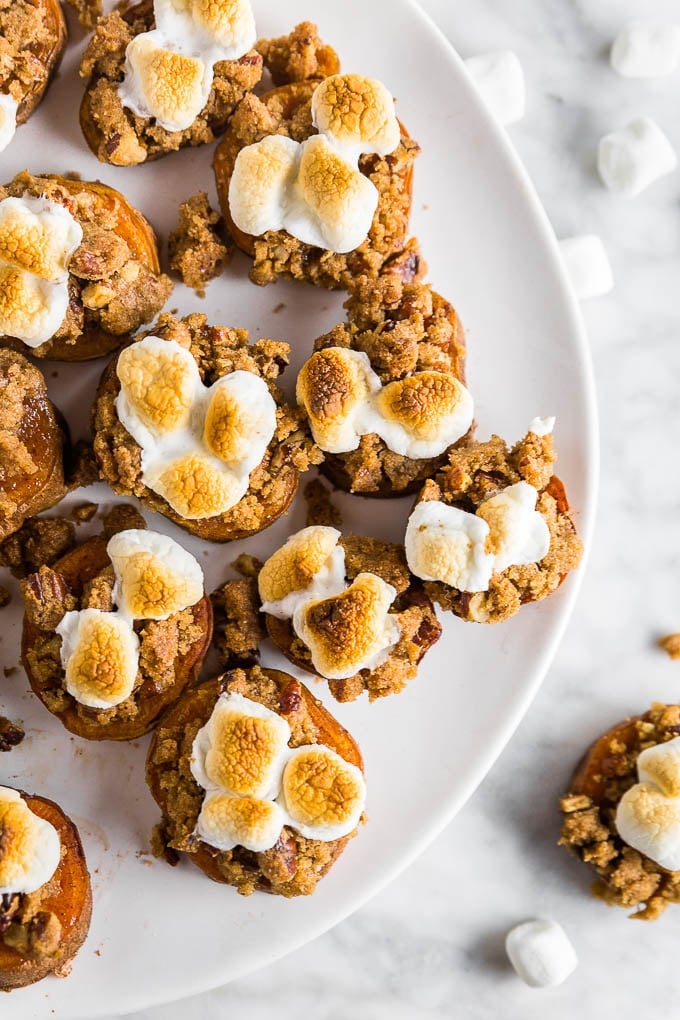 An overhead views of sweet potato casserole bites with marshmallows and brown sugar crumble on a white plate. 