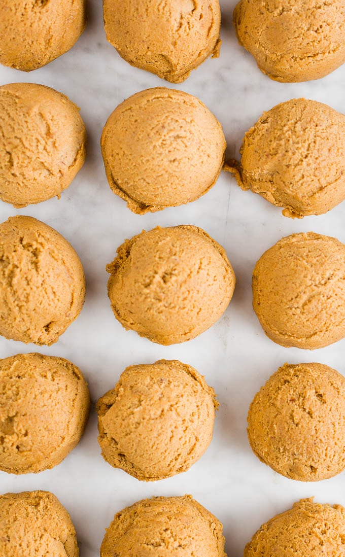 Balls of chewy ginger molasses cookie dough on parchment paper. 
