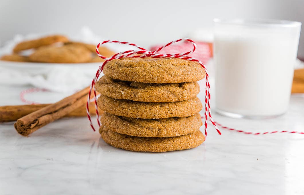 A stack of chewy ginger molasses cookies with a glass of almond milk.