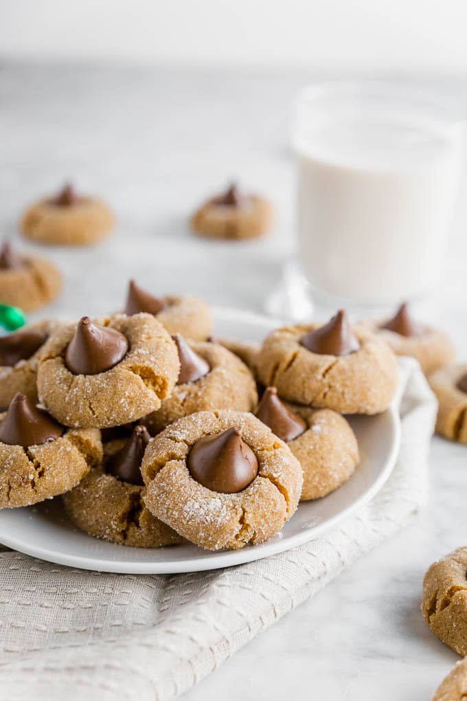 a plate of chocolate peanut butter blossoms with a glass of milk