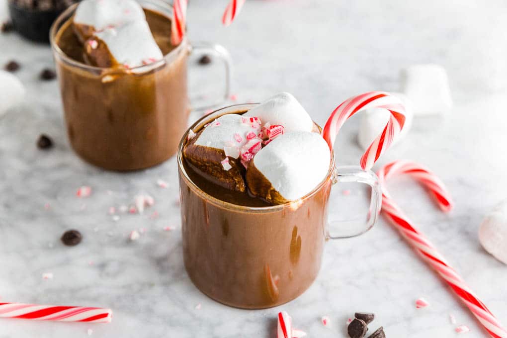 A few mugs of peppermint hot cocoa with candy canes, marshmallows and chocolate chips