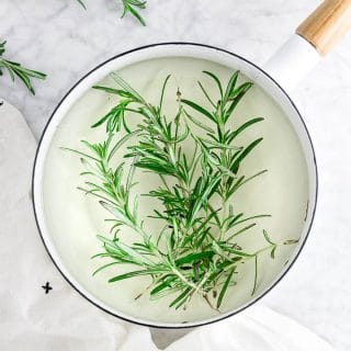 a saucepan filled with sugar, water and fresh rosemary to make rosemary infused simple syrup