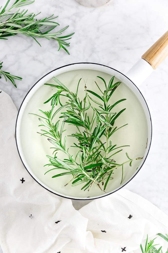 a saucepan filled with sugar, water and fresh rosemary to make rosemary infused simple syrup