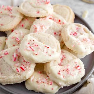 A plate of gluten-free white chocolate peppermint cookies with crushed candy canes on top.
