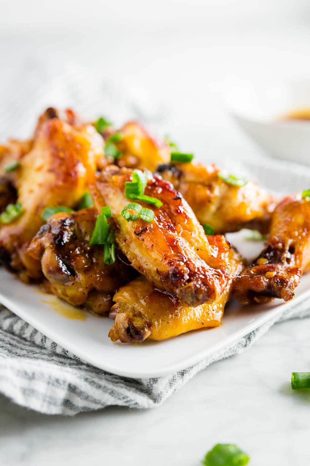 A plate of honey garlic chicken wings with green onions on top. 