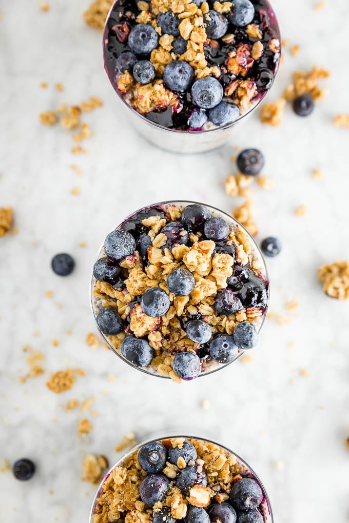 An overhead photo of three glasses of chia seed pudding topped with blueberries and Udi's Gluten Free Vanilla Granola in a row. 