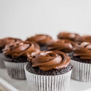 Photo of a gluten-free chocolate cupcake with chocolate frosting in a white cupcake liner.