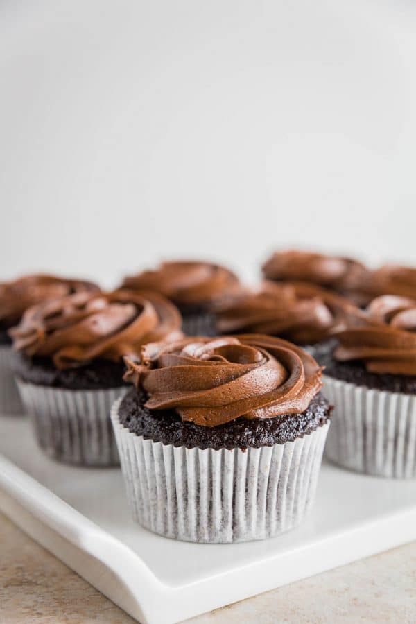 Photo of a gluten-free chocolate cupcake with chocolate frosting in a white cupcake liner.