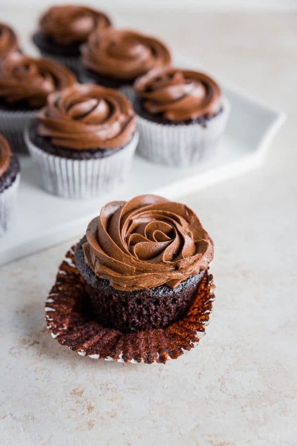 hoto of a gluten-free chocolate cupcake with chocolate frosting in a white cupcake liner.
