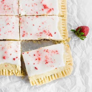 A photo of a giant strawberry pop tart covered with a powdered sugar glaze and freeze dried strawberries.