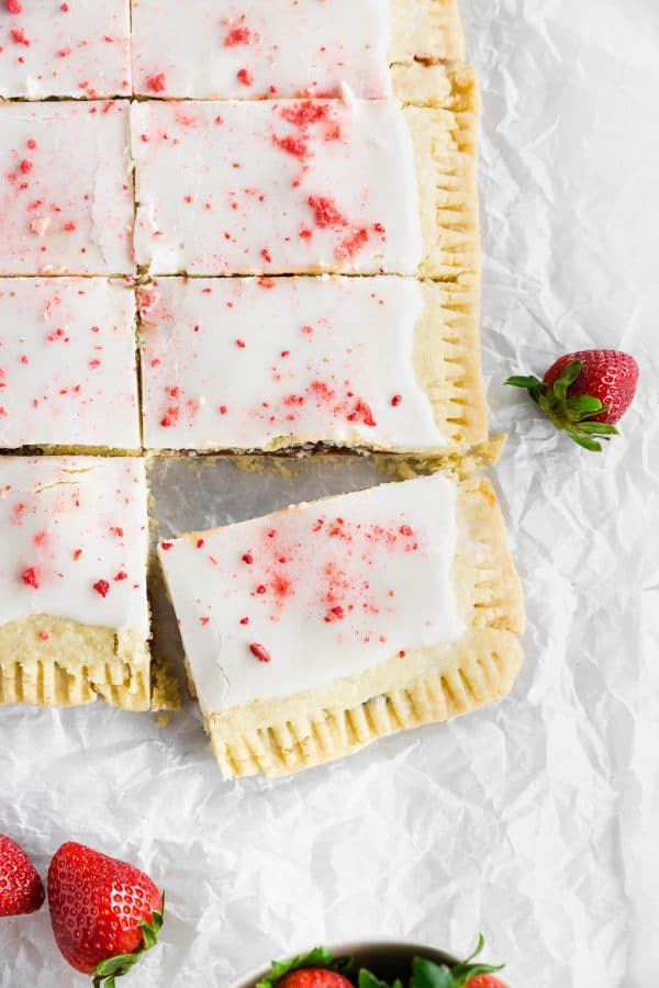 A photo of a giant strawberry pop tart covered with a powdered sugar glaze and freeze dried strawberries.