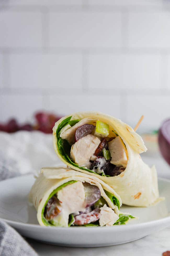 If you’re looking for an easy meal prep solution, this Gluten Free Chicken Salad Wrap using Mission Gluten Free Tortillas are just what you need. These tortillas are so soft and flavorful, they pair perfectly with this zesty chicken salad for an easy grab-and-go lunch option. #glutenfree #mealprep Photo of two gluten free chicken salad wraps on Mission Gluten Free tortillas on a plate with grapes.