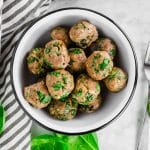 An overhead photo of a bowl of gluten free baked turkey meatballs filled with fresh spinach.